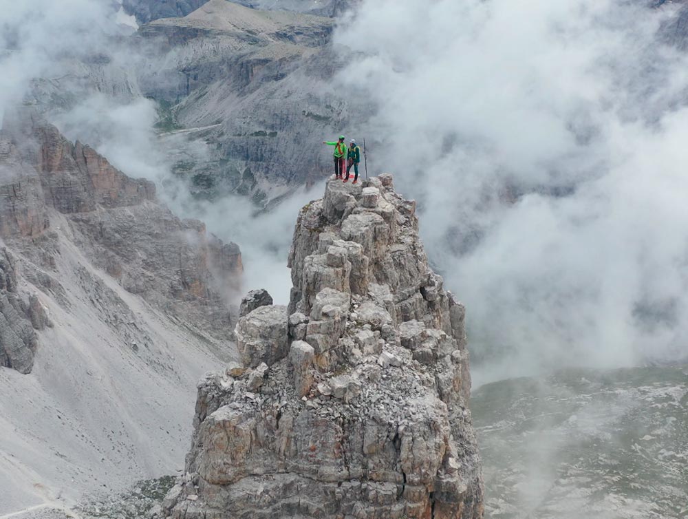Bergsteiger auf schmalem Gipfelgrat im Nebel als Sinnbild für mutige Entscheidungen und Risiko